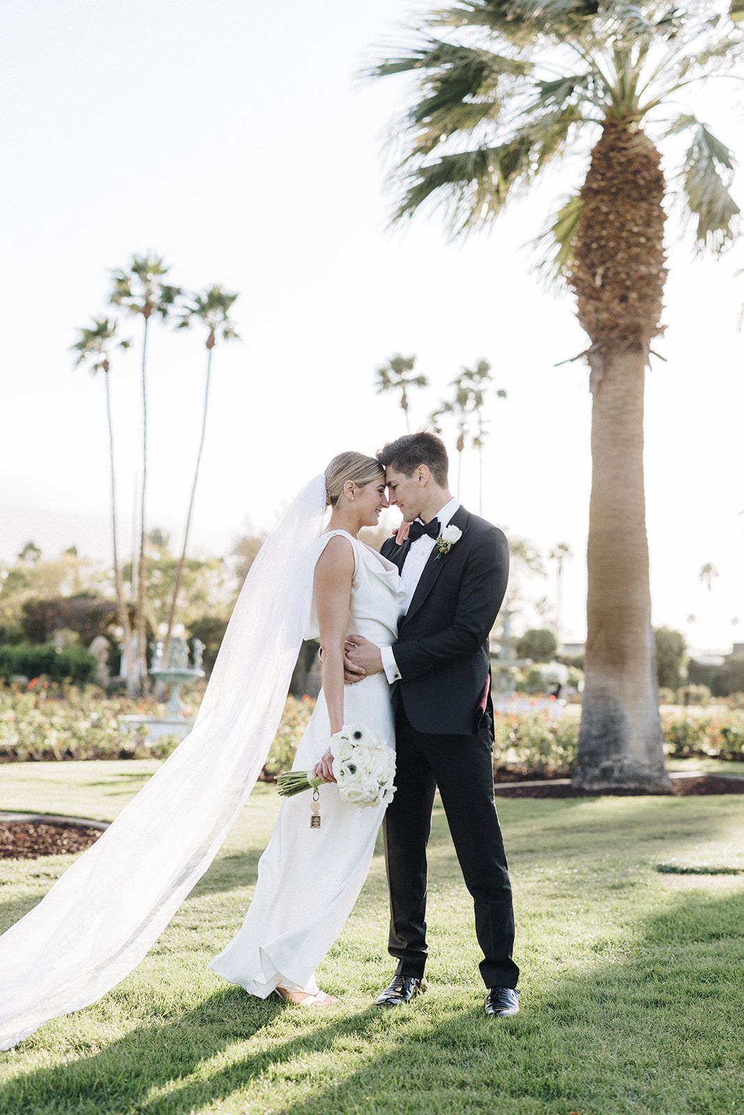 a female with blonde hair and a white wedding gown with her groom in an all black tux at their Coachella valley wedding