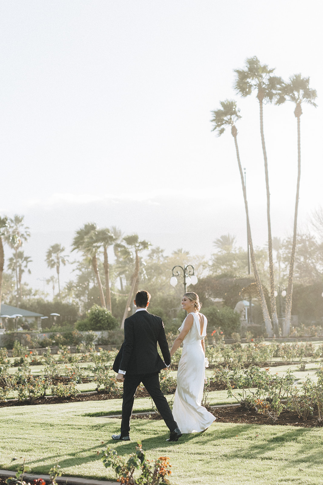 a female with blonde hair and a white wedding gown with her groom in an all black tux at their Coachella valley wedding