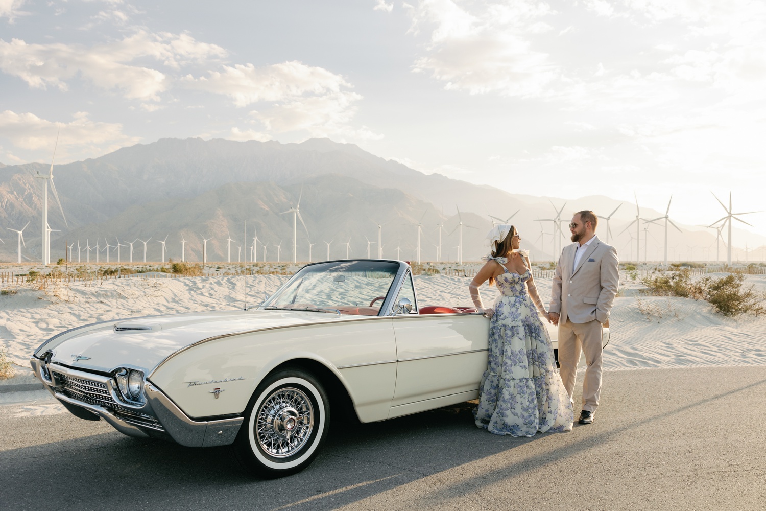 woman wearing a white with blue florals maxi dress and man in a tan linen suit posing for their California engagement photos