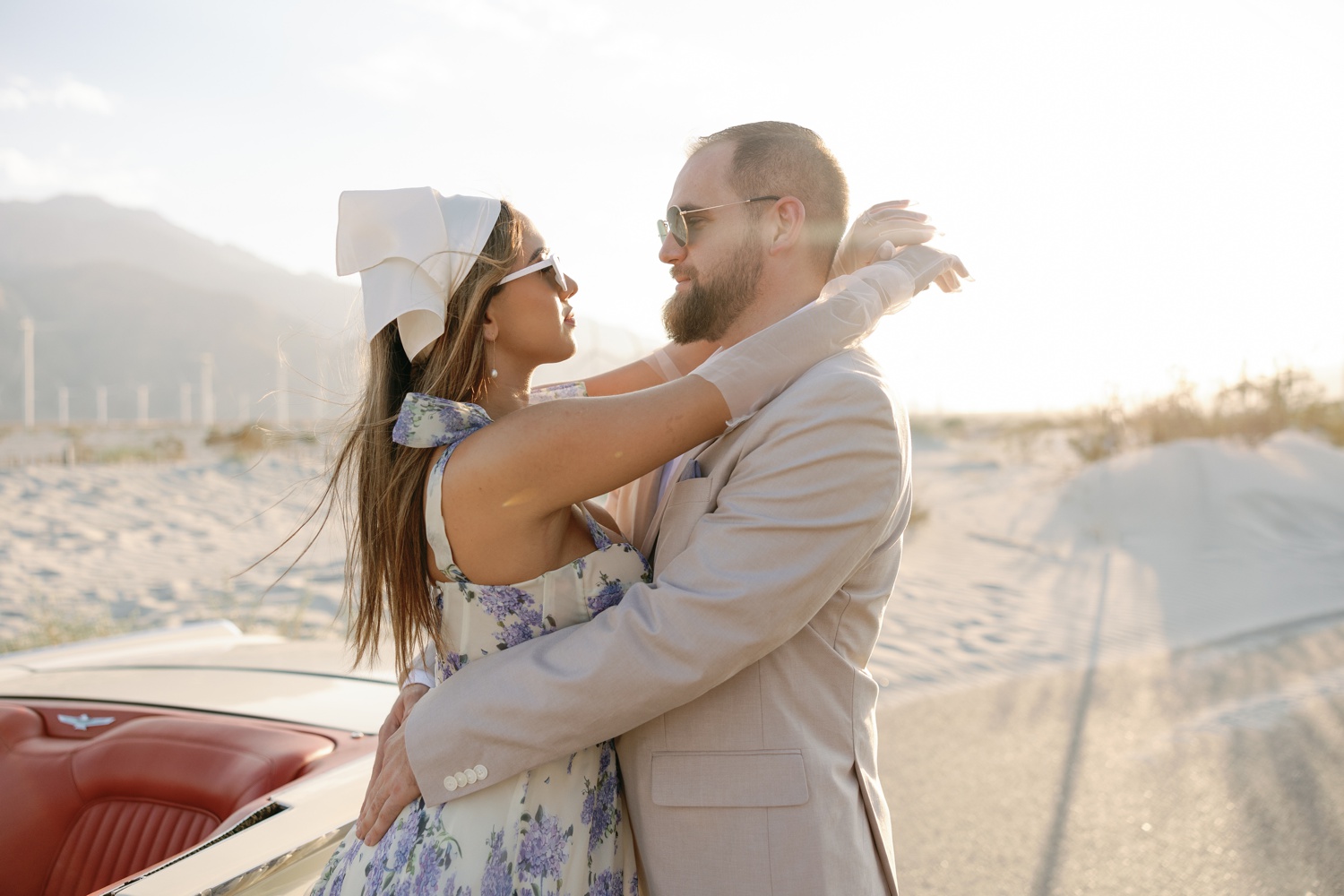 woman wearing a white with blue florals dress and man in a tan linen suit at their California engagement photos