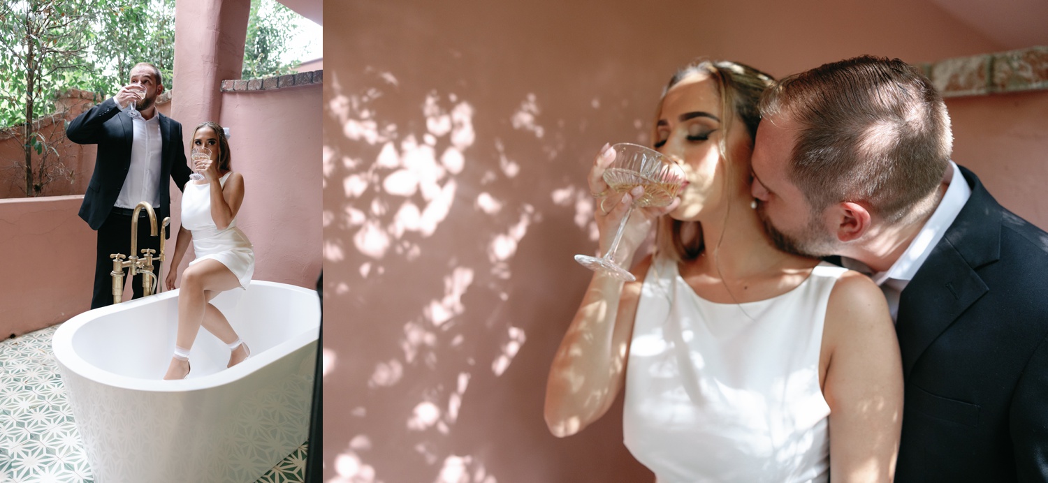a woman in white mini dress and a man in a black suit drinking champagne for their California engagement photos
